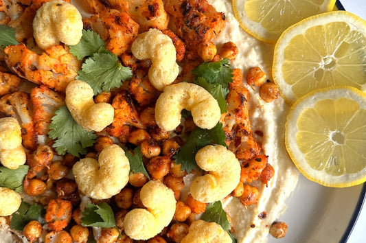 Close up of roasted cauliflower and chickpeas with feta, decorated with lemons